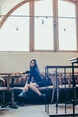 Siyah elbise giyen zarif esmer kız bir sokak kafesinde dinleniyor. Reklamcılık, moda. Renkli fotoğraf