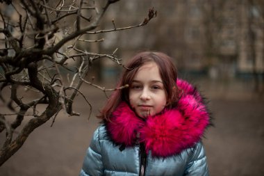 Mavi vejetaryen ve sahte kürklü genç ve tatlı bir kadın şehir arka planında poz veriyor. Moda tarzı kıyafetler.