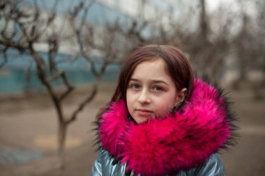 Mavi vejetaryen ve sahte kürklü genç ve tatlı bir kadın şehir arka planında poz veriyor. Moda tarzı kıyafetler.