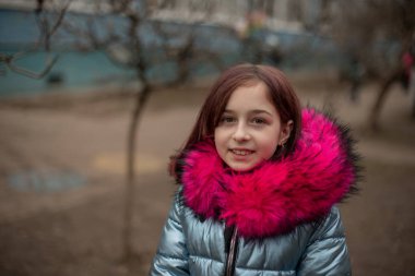 Mavi vejetaryen ve sahte kürklü genç ve tatlı bir kadın şehir arka planında poz veriyor. Moda tarzı kıyafetler.