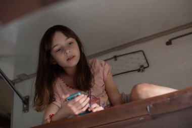 Trenin en üst rafında yatan tatlı kız. Yaz tatili. Kız akıllı telefondan selfie çekiyor..