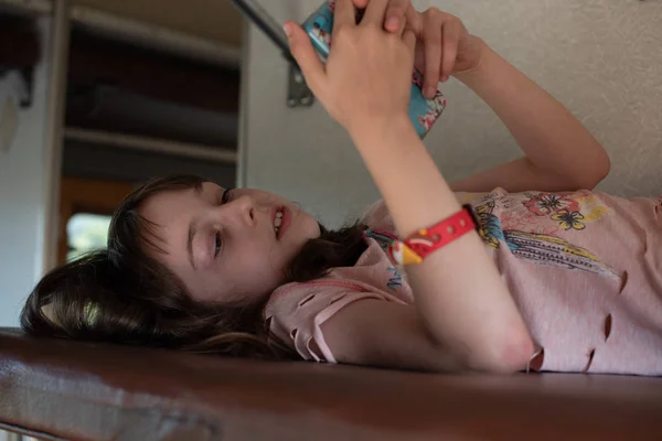 Linda chica acostada en el estante superior en el tren. Vacaciones de verano. Chica hace selfie en un teléfono inteligente . — Foto de Stock