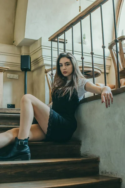 Bella ragazza bruna elegante che indossa un vestito nero si rilassa in un caffè di strada. Pubblicita ', moda. Foto colorata — Foto Stock