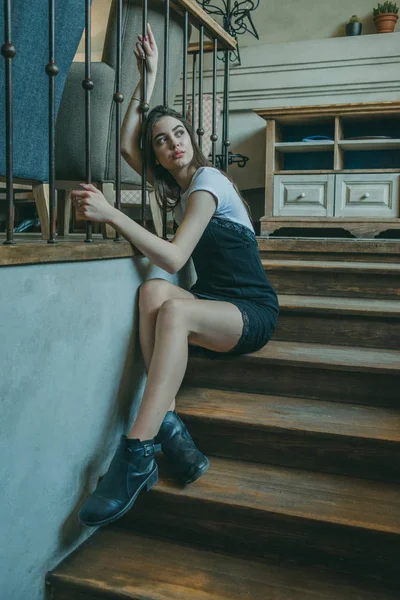 Bella ragazza bruna elegante che indossa un vestito nero si rilassa in un caffè di strada. Pubblicita ', moda. Foto colorata — Foto Stock