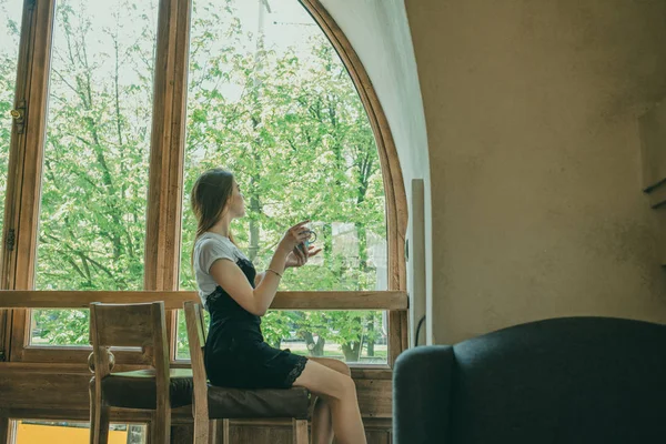 Schöne elegante brünette Mädchen in einem schwarzen Kleid entspannt in einem Straßencafé. Werbung, Mode. getöntes Foto — Stockfoto