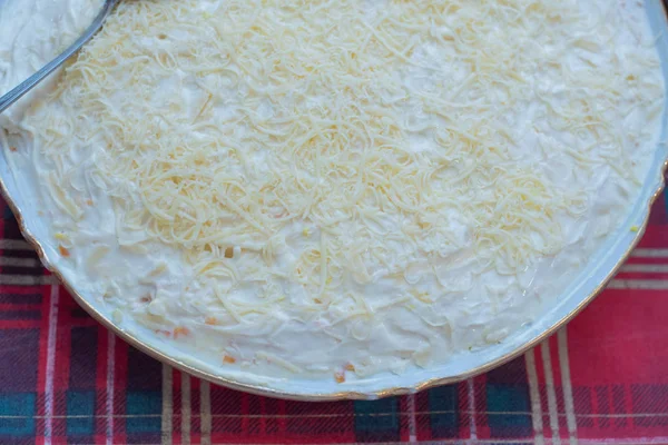 Νόστιμη σαλάτα Mimosa από πατάτες, σαρδέλες, κρεμμύδια, αυγά, καρότα, τυρί σε πιάτο σε τραπέζι — Φωτογραφία Αρχείου