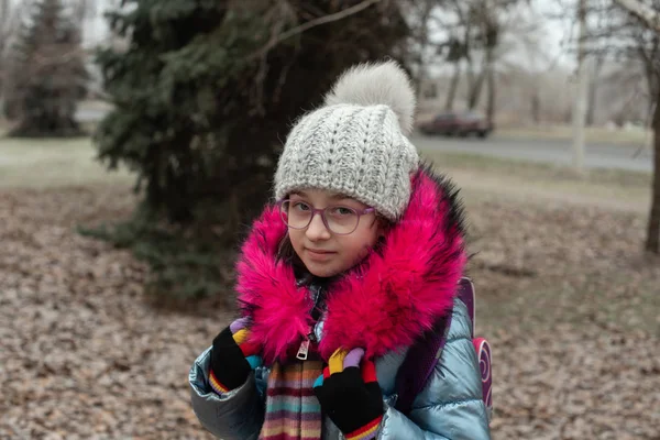 Close up portrait of a beautiful nine year old little girl in autumn park. 9 years old girl in a hat and a blue jacket. — Stock Photo, Image