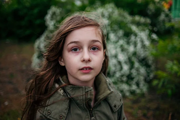 Holčička na ulici na pozadí zeleného listí. Dívka s dlouhými vlasy. Dítě 9-10 let dívka. — Stock fotografie