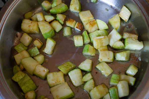 Grönsaker styckade i kuber stekta på stekpanna, i köket.Zucchini stekt i kuber i en stekpanna — Stockfoto