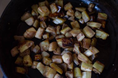 Sebzeler kızartma tavasında, mutfakta küp şeklinde kesilmiş. Tavada kızartılmış patlıcan.