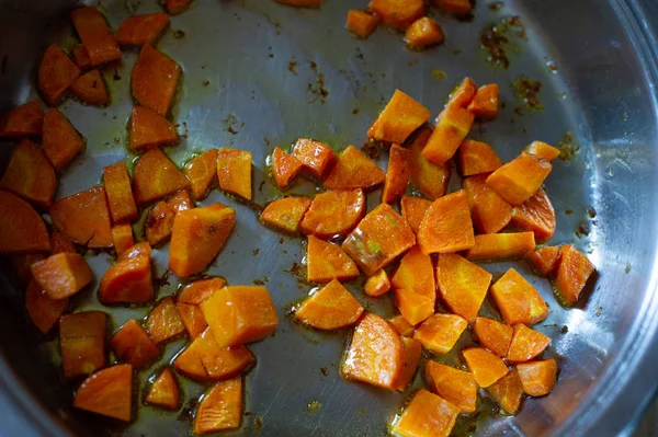 Овочі розрізаються кубами, смаженими на сковороді, на кухні. Морква смажена в кубах у сковороді. Морква — стокове фото
