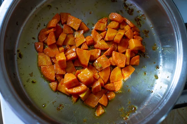 Овощи нарезаны кубиками, обжаренными на сковороде, на кухне. Морковь, обжаренная кубиками в кастрюле. Морковь — стоковое фото
