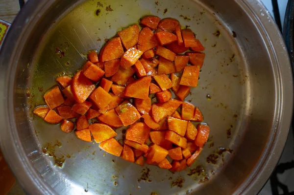 Grøntsager skåret i terninger stegt på stegepande, i køkken. Gulerod stegt i terninger i en gryde. Gulerod - Stock-foto