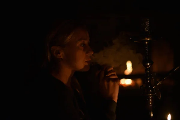 Girl. Hookah. Girl smokes a hookah by candlelight.
