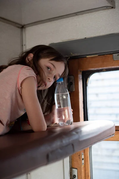 Chica en un paseo en un viejo tren. Cerca hay una botella de agua . — Foto de Stock