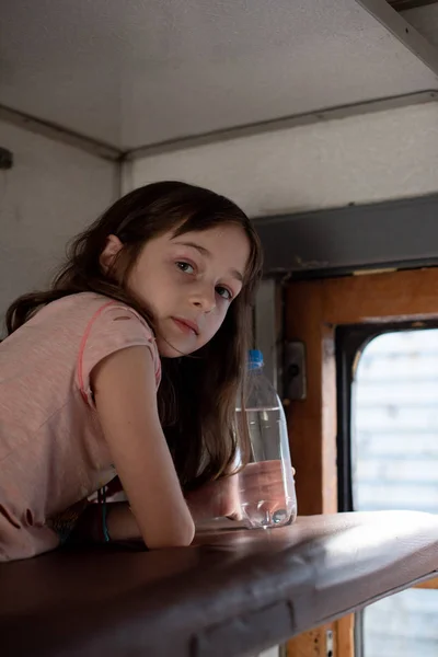 Chica en un paseo en un viejo tren. Cerca hay una botella de agua . — Foto de Stock