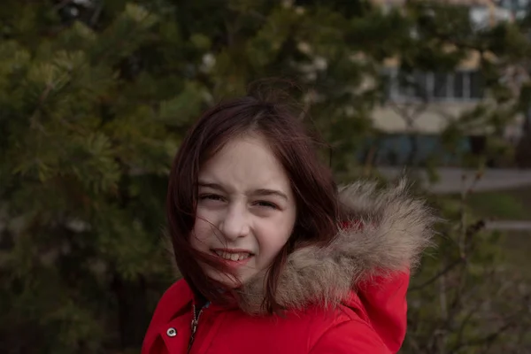 Portrait of a cute little girl of 8-9 years old, wearing bright red jacket — Stock Photo, Image