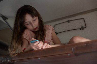 Trenin en üst rafında yatan tatlı kız. Yaz tatili. Kız akıllı telefondan selfie çekiyor..