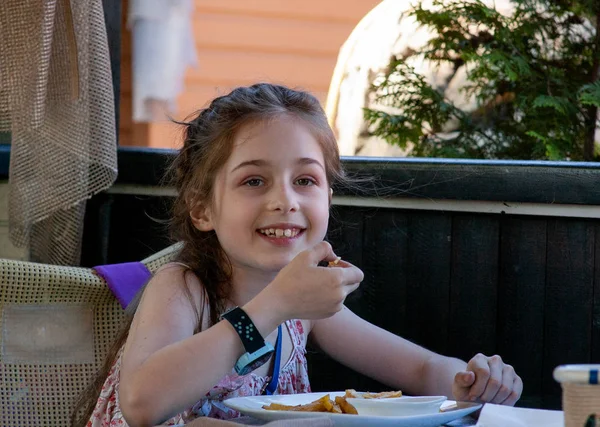 El niño come. La niña come papas fritas. chicas de 9 años. Café al aire libre en la calle . — Foto de Stock