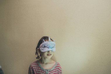 Yüzünde yumuşak, beyaz, uykulu tek boynuzlu at olan düz saçlı bir kız. Tek boynuzlu at maskeli kız. 9 yaşında..