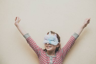 Yüzünde yumuşak, beyaz, uykulu tek boynuzlu at olan düz saçlı bir kız. Tek boynuzlu at maskeli kız. 9 yaşında..