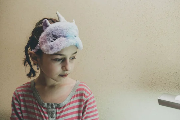Mädchen mit glatten Haaren mit einem weichen weißen schlafenden Einhorn auf dem Gesicht. Mädchen in Einhorn-Schlafmaske. 9 Jahre alt. — Stockfoto
