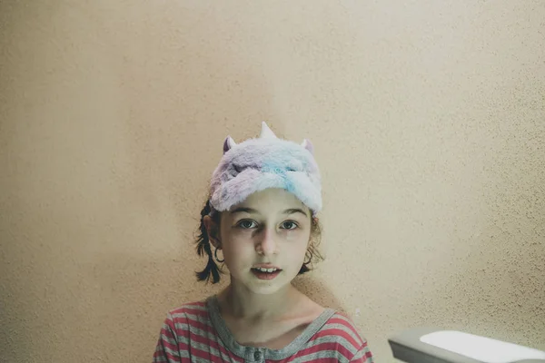 Κορίτσι με ίσια μαλλιά με ένα απαλό λευκό κάλυμμα ύπνου Μονόκερος στο πρόσωπό της. Κορίτσι με μάσκα ύπνου μονόκερου. 9 ετών. — Φωτογραφία Αρχείου