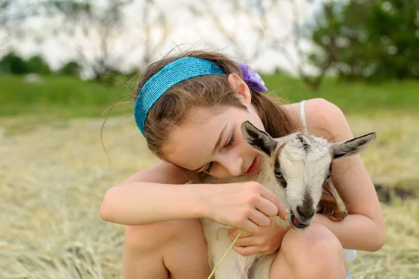 Chica con cabra bebé en la granja al aire libre. Animales del pueblo. feliz niño abraza cabra, concepto de unidad de la naturaleza y el hombre . — Foto de Stock