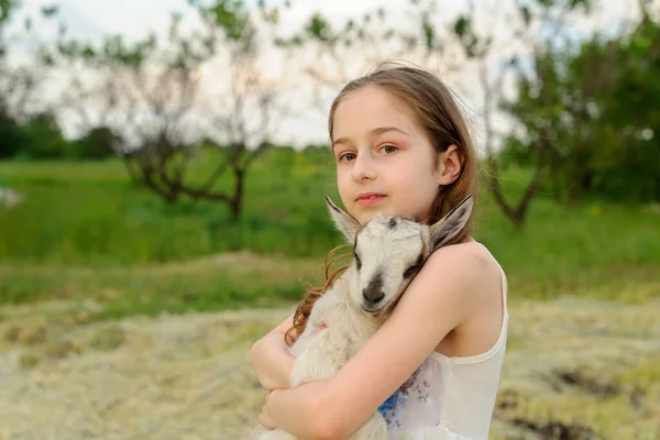 Dziewczyna z kozłem na farmie. Wiejskie zwierzęta. szczęśliwy dziecko przytula kozy, koncepcja jedności natury i człowieka. — Zdjęcie stockowe