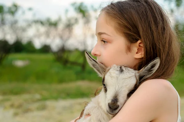 Girl with baby goat on farm outdoors. Village animals. happy child hugs goat, concept of unity of nature and man. — Stock Photo, Image