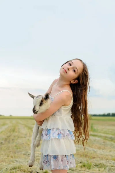 Menina com cabra bebê na fazenda ao ar livre. Animais de aldeia. criança feliz abraços cabra, conceito de unidade da natureza e do homem . — Fotografia de Stock