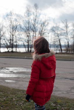 Parlak kırmızı ceket giyen, 8-9 yaşlarında şirin bir kızın portresi.