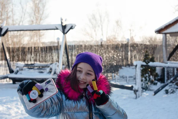 Femme souriante avec téléphone portable marchant dans la rue. Fille 9 ans dans la rue en hiver tenant un téléphone — Photo