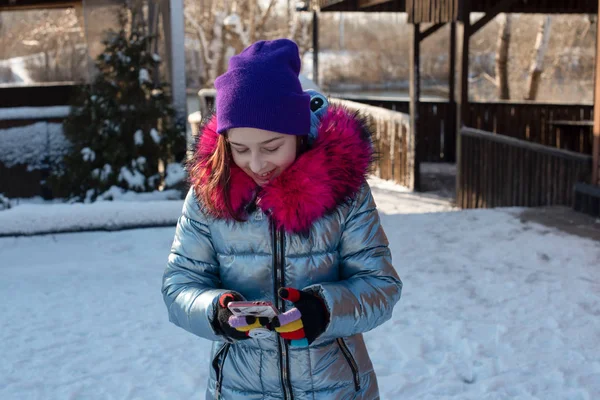 Mujer sonriente con teléfono móvil caminando por la calle. Chica de 9 años en la calle en el invierno sosteniendo un teléfono — Foto de Stock