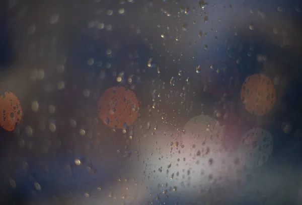 Window in drops rain and the glare lights