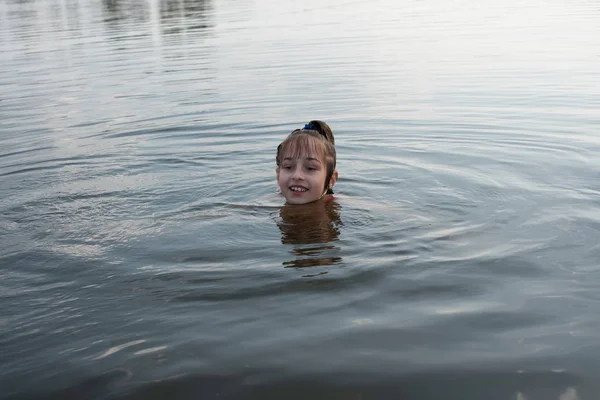 Ευχαρίστηση όμορφο κοριτσάκι κολύμπι σε μπλε νερά, άπαχο έξω από το νερό και χαμόγελο. Η έφηβη απολαμβάνει τον ζεστό καιρό. — Φωτογραφία Αρχείου