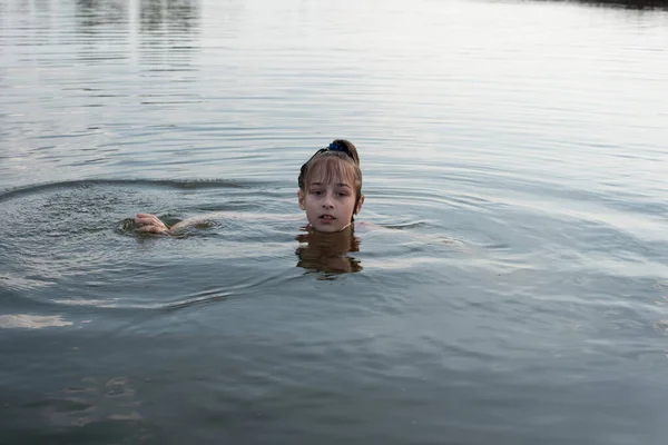 Placer hermosa niña nadar en agua azul, inclinarse fuera del agua y sonreír. Adolescente chica disfruta del clima cálido —  Fotos de Stock