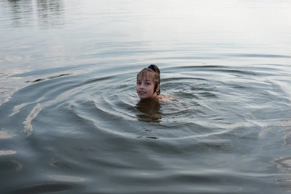 Удовольствие красивая маленькая девочка плавает в голубой воде, наклоняется из воды и улыбается. Девочка-подросток наслаждается теплой погодой Лицензионные Стоковые Изображения