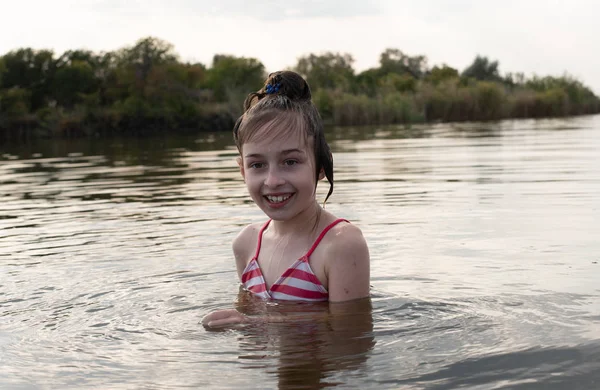 Placer hermosa niña nadar en agua azul, inclinarse fuera del agua y sonreír. Adolescente chica disfruta del clima cálido —  Fotos de Stock