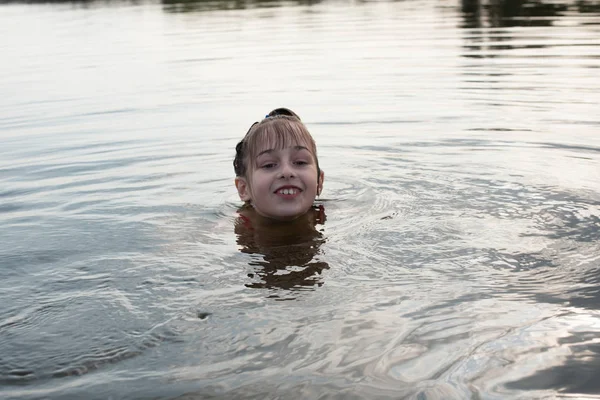 Placer hermosa niña nadar en agua azul, inclinarse fuera del agua y sonreír. Adolescente chica disfruta del clima cálido —  Fotos de Stock