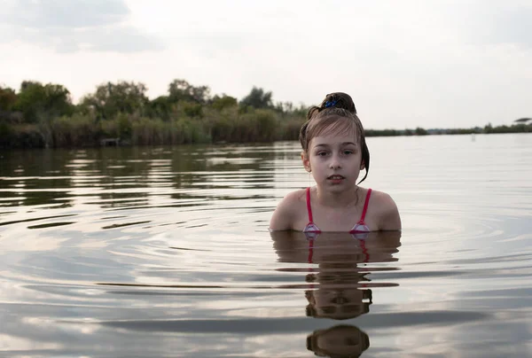 Placer hermosa niña nadar en agua azul, inclinarse fuera del agua y sonreír. Adolescente chica disfruta del clima cálido —  Fotos de Stock