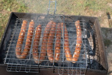 Kazıkta ızgarada sosisler. Gün batımında doğada bir piknik.