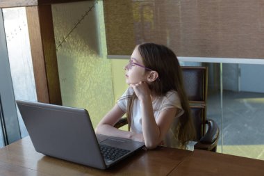 Genç ve çekici bir bayan modern kahve dükkanında otururken dizüstü bilgisayar kullanıyor. Kız ve dizüstü bilgisayar.