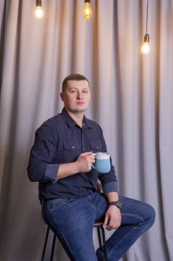 Adam mavi fincanla kahve ya da çay içiyor..