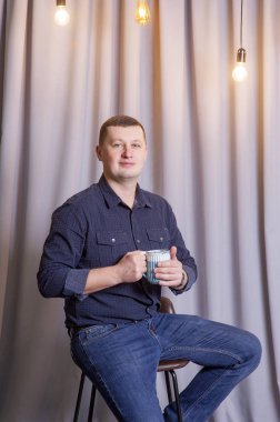 Adam mavi fincanla kahve ya da çay içiyor..