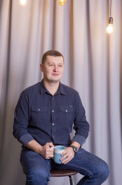 Adam mavi fincanla kahve ya da çay içiyor..