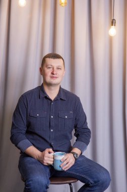 Adam mavi fincanla kahve ya da çay içiyor..