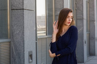 Mavi elbiseli güzel bir kız bir kafenin arka planında cadde boyunca yürüyor. Caddedeki kafede mavi elbiseli bir kız. Yaz. Bahar. Şehir portresi kadını. Güzellik.