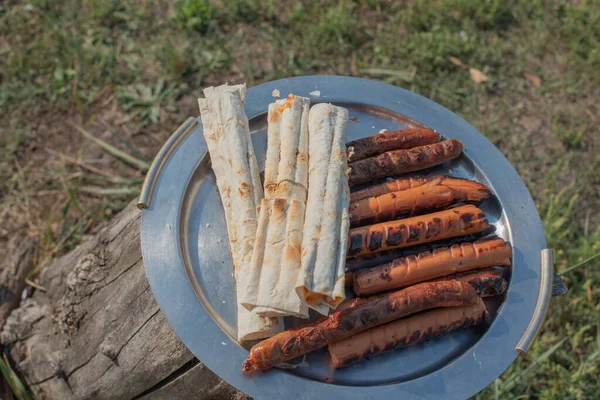 ピタパンにソーセージを焼きます 焼きピタパンとソーセージ 金属板やトレイ上のピタパンとソーセージ ストリートフード ピクニック 暖かい天気の中でリラックスした 食品写真 夏休み — ストック写真