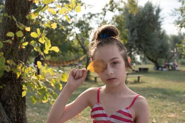 穿着泳衣 头戴黄叶 长着一棵树的女孩 女孩9岁在度假 一个青少年的肖像 一个穿着泳衣的女婴的画像 青少年 — 图库照片